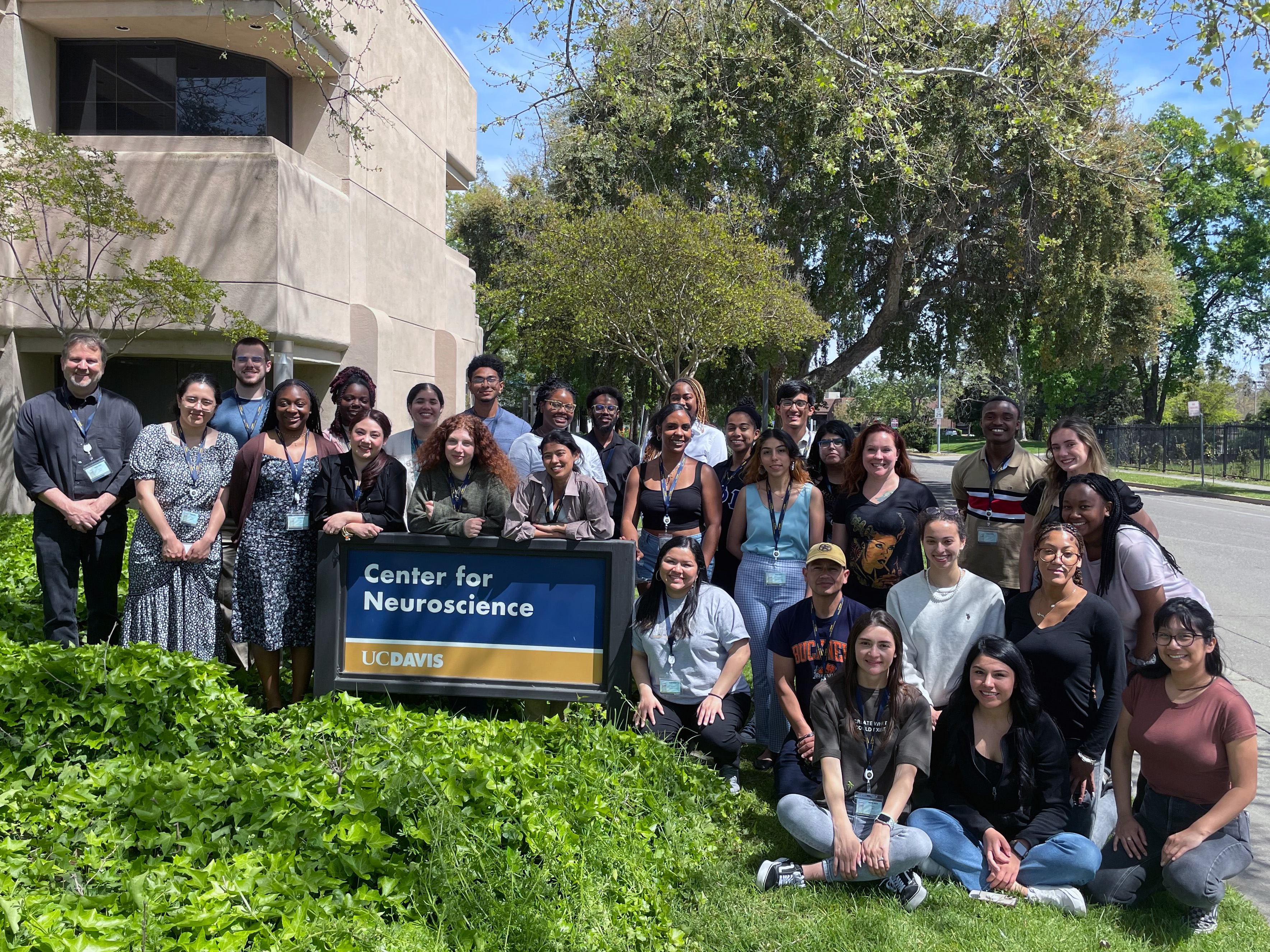 30 people posing for a group photo outside in front of the UC Davis Center for Neuroscience sign